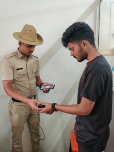 A Karnataka police officer recording the fingerprint of a youth on the M-CCTNS. (Supplied)