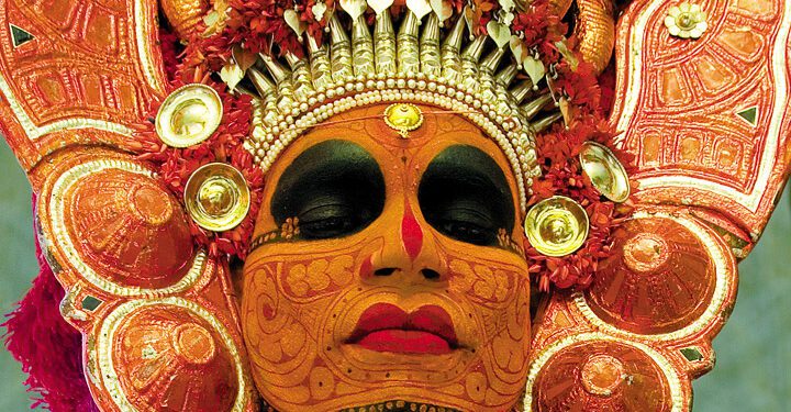 Primary and secondary colours are used to paint the theyyam performer's face and body. (Supplied)