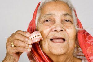 Imagen representativa de una anciana mostrando su dentadura postiza. 