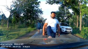One of the assailants stepping on Arun's car and warning them