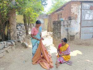 Samakka showing her Bathukamma saree, as her neighbour looks on. (Sumit Jha/South First)